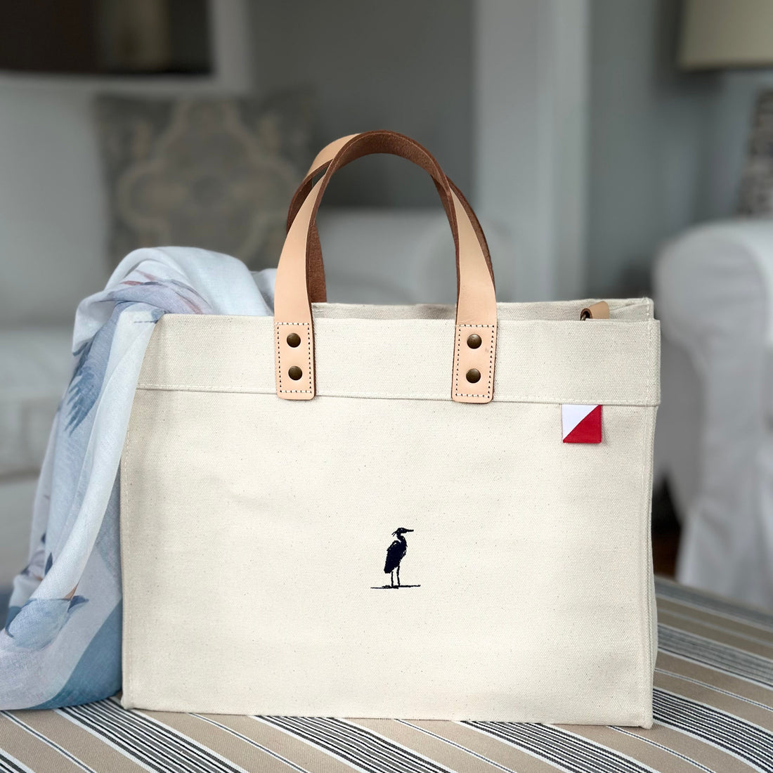 Beige tote bag with brown leather handles on a striped surface - Eastern Shore Co Bags