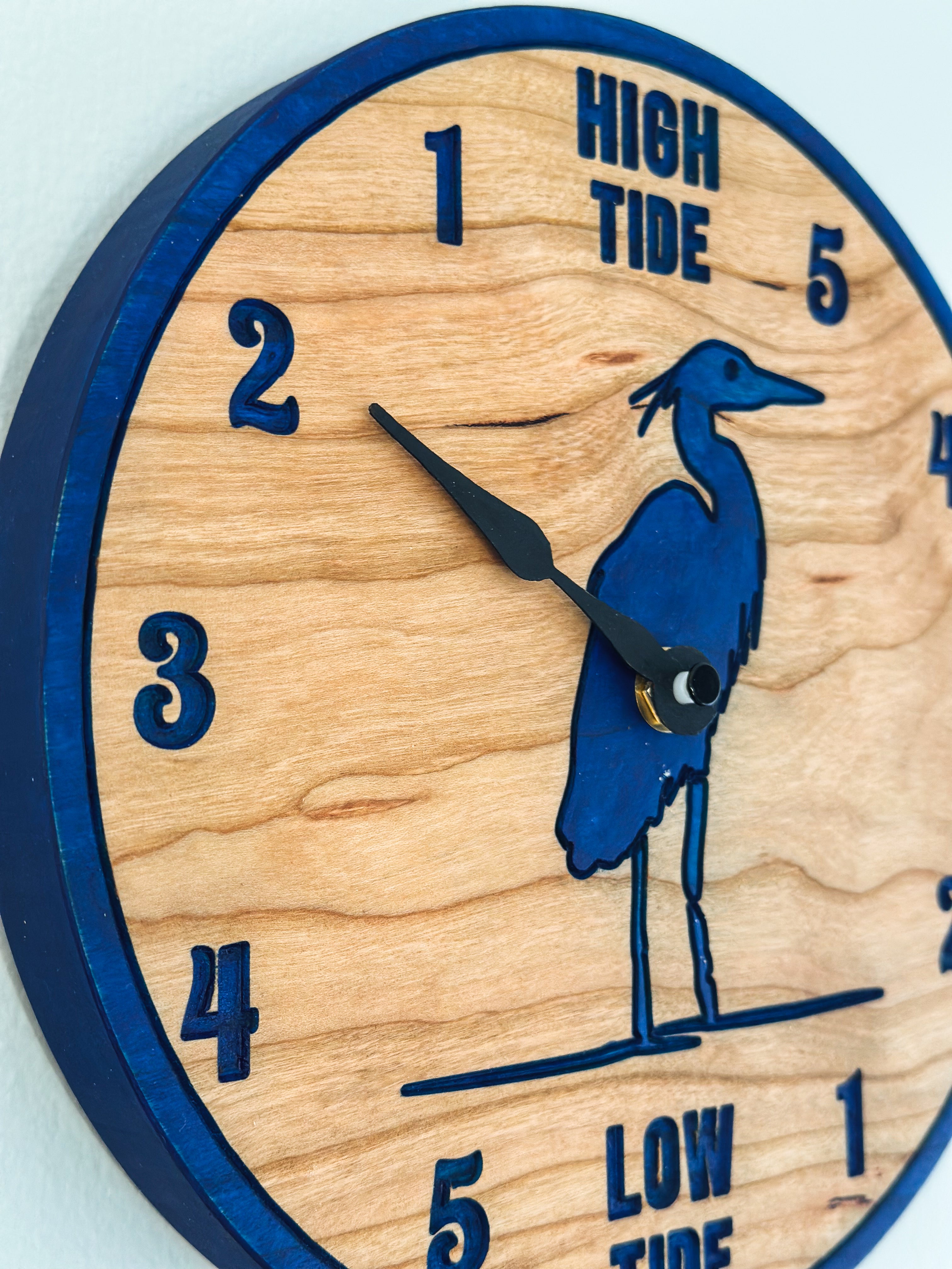 Wooden clock with blue heron design and tide markings on a light background