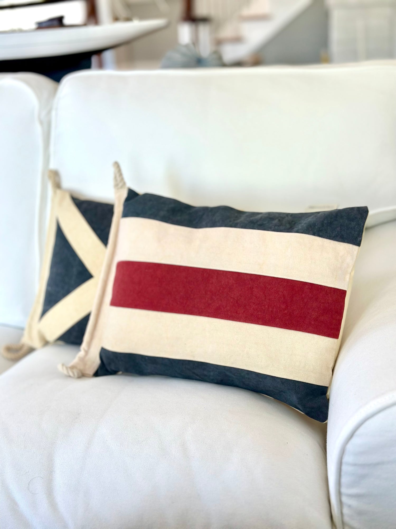 Decorative pillow with red, white, and blue stripes on a white couch.