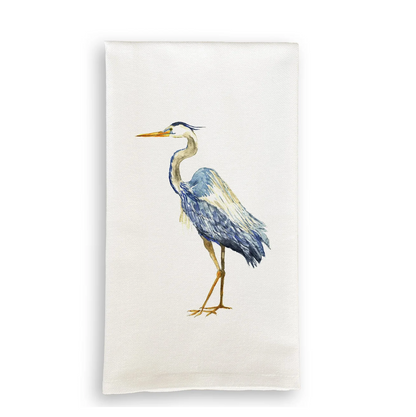 An off-white fabric tea towel featuring a watercolor illustration of a blue-gray heron with yellow accents, shown against a plain white background. heron tea towel, coastal tea towel, Chesapeake Bay decor, Eastern Shore decor, coastal kitchen decor, Great Blue Heron gift, nautical kitchen, Eastern Shore gift, cotton tea towel, coastal hostess gift