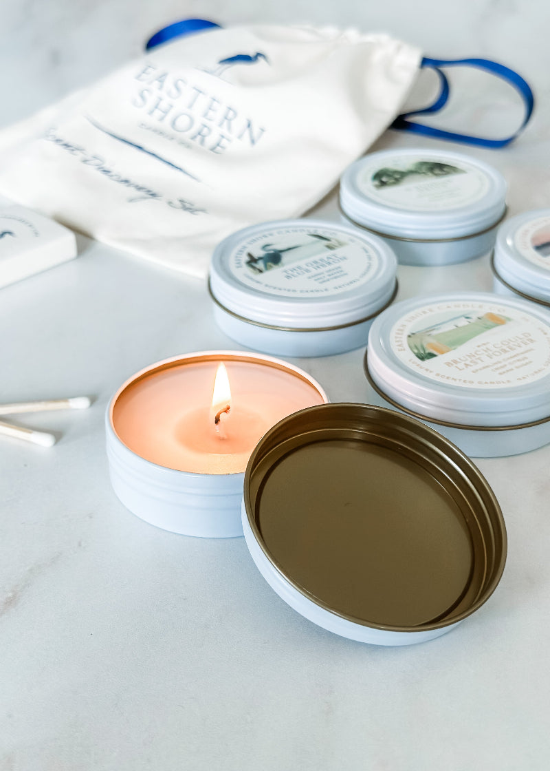A set of candle tins with various labels, one tin is open with a lit candle, and heron wooden matches are also shown.

Signature TIn Set