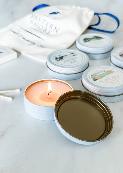 A set of candle tins with various labels, one tin is open with a lit candle, and heron wooden matches are also shown.

Signature TIn Set