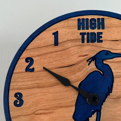 Wooden clock with blue heron design and high/low tide markings on a white background